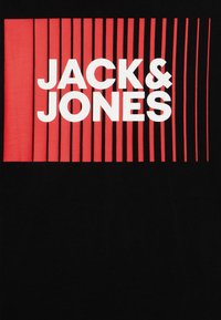 Juodas marškinėliai su raudonu stačiakampiu dizainu ir vertikaliomis juostelėmis, o baltais didžiosiomis raidėmis užrašyta "JACK & JONES".