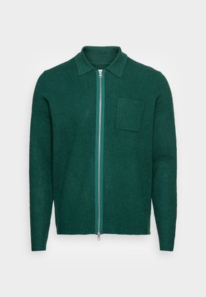 Suéter de manga larga con cremallera en color verde oscuro, con cuello y un solo bolsillo en el pecho, mostrado sobre un fondo blanco.