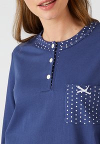 Camicia a maniche lunghe blu navy con colletto a pois, quattro bottoni e taschino con motivo a pois e dettaglio a fiocco.