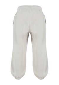 Lys grå sweatpants med elastisk talje, sidelommer og tætsiddende manchetter ved anklerne. Blødt stof med minimal tekstur.