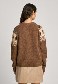 Maglione marrone lavorato a maglia con dettagli a motivo nei toni di crema e blu sulle spalle, caratterizzato da un collo rotondo e polsini a coste.