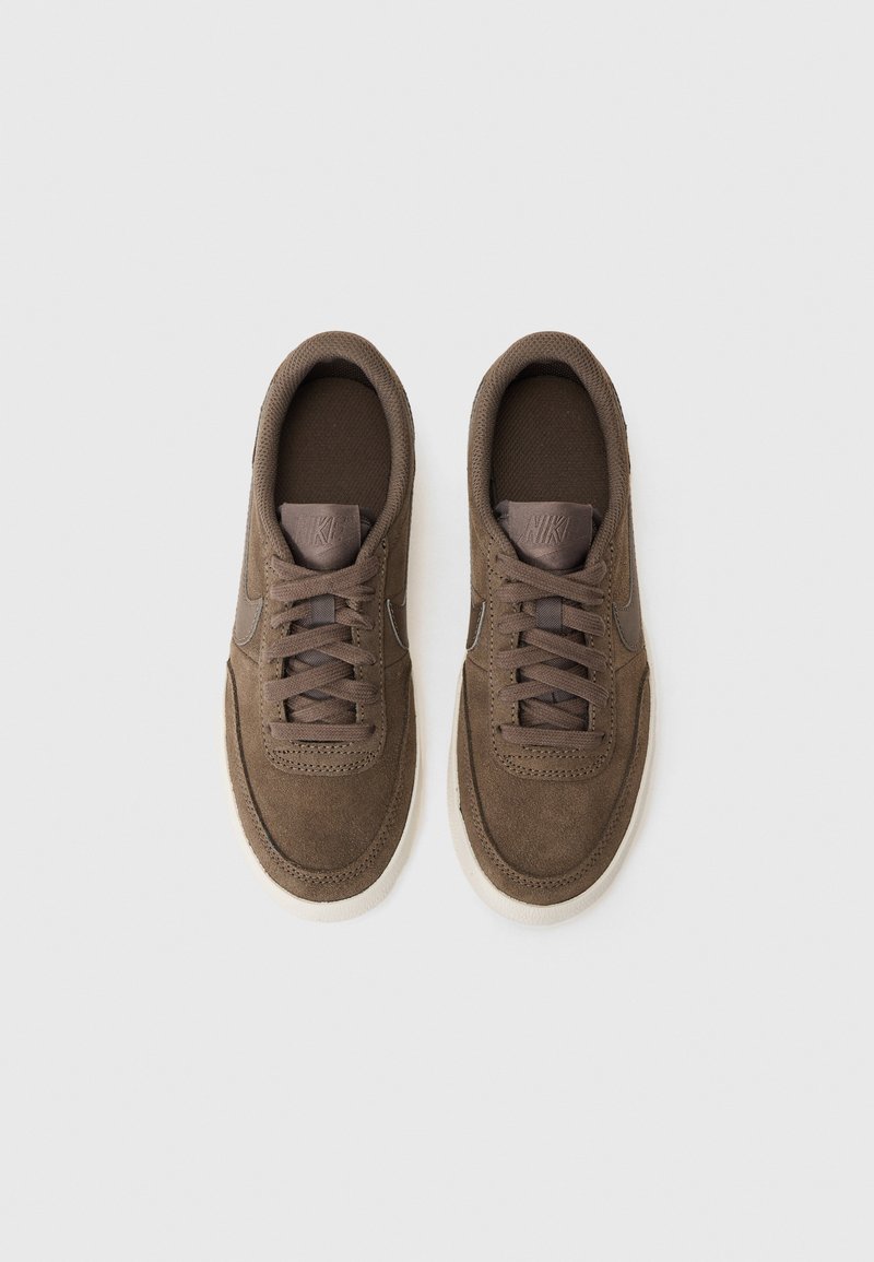 Zapatillas marrones con parte superior de ante y tejido, punta redondeada, detalles cosidos y cordones planos. Suela de goma blanco crema con acentos mínimos.