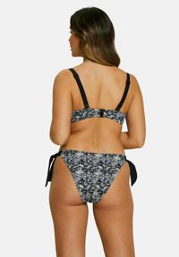 Bikini imprimé serpent noir et bleu avec des bretelles réglables et un bas à nouer, mettant en valeur un tissu texturé et un design ajusté.