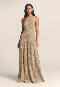 Šviesiai smėlio spalvos maxi suknelė su juodu gėlių raštu, be rankovių, su halterio kaklu ir plačia suknele. Lygi audinio tekstūra.