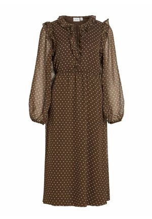 Brun kjole med polkadotter, med volang på halsen og lange, semitransparente ermer. Innsvingt midje, flytende skjørt og knyting ved halsen.