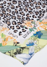 Foulard in seta con stampa leopardata e motivi floreali nelle tonalità di arancione, blu e verde, con un logo di marca ben visibile in un angolo.