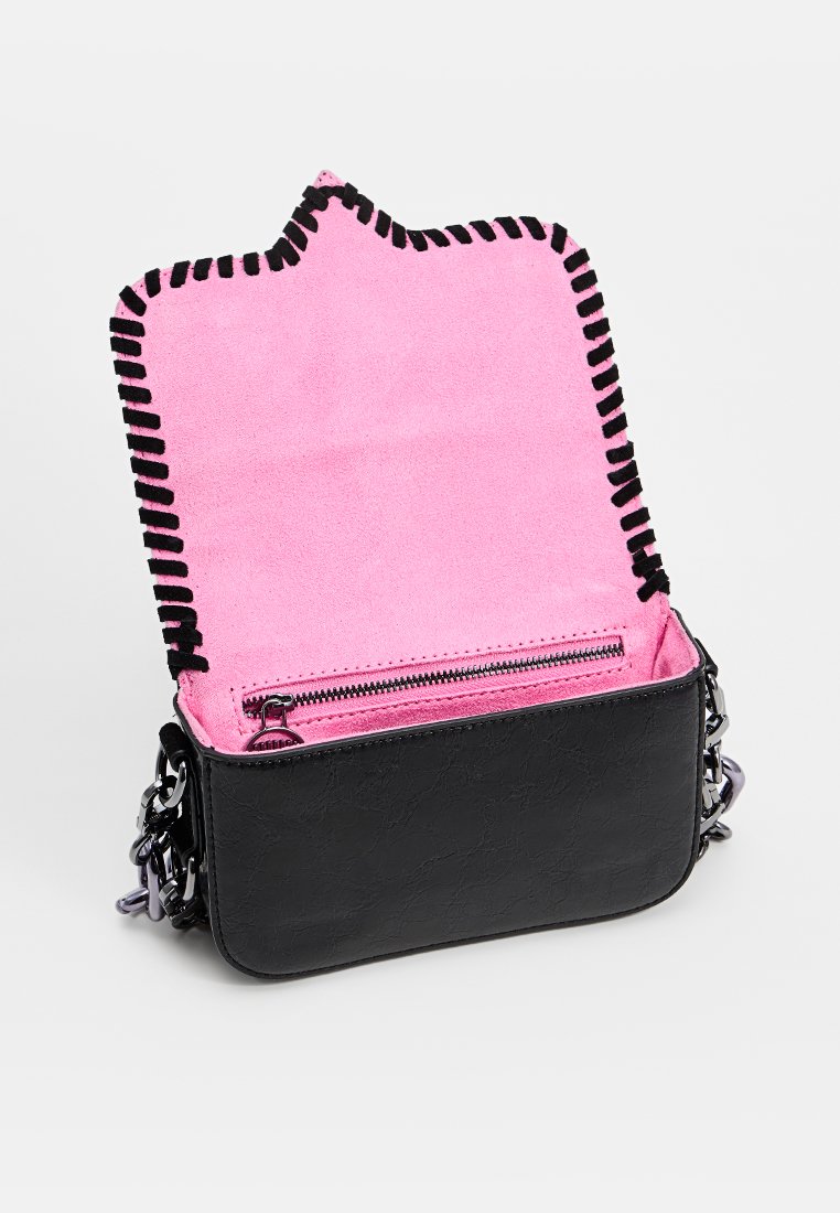 Sac en cuir noir porté croisé avec un intérieur en suède rose, comprenant une poche zippée et des coutures noires le long des bords.