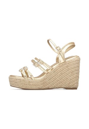 Sandalia de cuña dorada con tres correas, con detalles de piedras preciosas; plataforma de textura tejida; punta redondeada; correa ajustable en el tobillo.