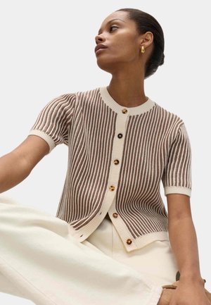 Brun og creme stribet strikket cardigan med korte pufærmer, rund halsudskæring og store gyldne knapper. Båret over cremefarvede bukser.