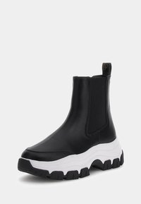 Stivali neri alla caviglia con pannelli laterali elasticizzati, parte superiore in pelle liscia e suola bianca spessa con battistrada textured nera.