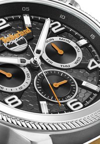 Orologio nero e argento con un quadrante a motivo esagonale, accenti arancioni e tre sottodial. Presenta marcatori orari numerici audaci.
