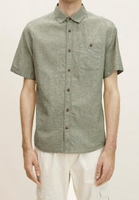 Camisa de lino mezclado verde de manga corta con cuello abotonado, botones marrones y bolsillo en el pecho. Textura suave, corte casual.