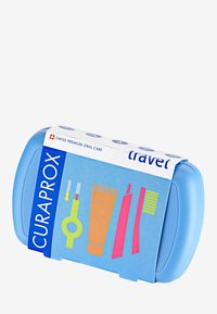 Kit de soins bucco-dentaires de voyage Curaprox dans un étui en plastique bleu. Comprend des illustrations colorées d'outils et de produits dentaires sur l'emballage.