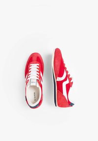 Zapatillas atléticas de ante rojo con acentos blancos, que cuentan con una suela acolchada y un detalle en azul marino en contraste. Cierre con cordones y diseño de puntera redondeada.