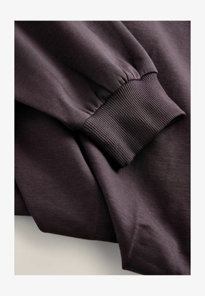 Dark purple sweatshirt fabric, featuring a ribbed cuff with elastic. Smooth texture, layered appearance with soft draping.