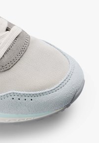 Sneaker avec un dessus en maille crème texturée, des accents en daim gris et une coque en daim bleu clair. Présente une semelle en caoutchouc avec un design subtil.