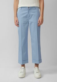 Pantaloni in cotone azzurro chiaro con una vestibilità rilassata, fronte piegato e orli arrotolati. Abbinati a sneaker bianche per un look casual.