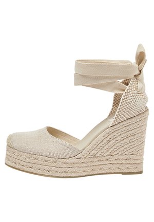 Beige wedge espadrilles with a woven textured upper and ankle straps. The heel features braided jute detailing, adding a natural look.