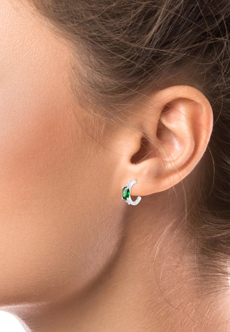 Pendiente de aro de plata con una piedra preciosa verde, de diseño elegante y superficie texturizada, colocado en la oreja.