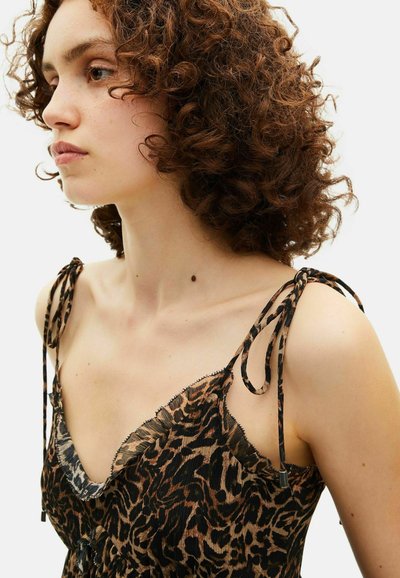 Top à motifs léopard avec de fines bretelles à nouer, bords effilochés et décolleté plongeant ; fabriqué en tissu léger avec une surface texturée.