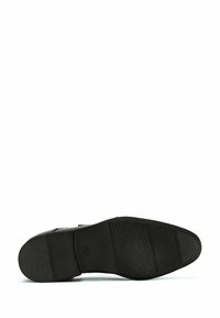 Musta kumipohja kengälle, jossa on kuvioituja uria ja kuvioita pitoon. Pyöreä muoto, sileä viimeistely ja hillitty logodetaili.