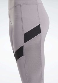 Leggings atletici grigi chiari con un pannello di accentatura nera, lato testurizzato e tessuto liscio con dettagli di cucitura visibili.