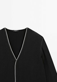 Top noir à manches longues avec col en V et surpiqûres blanches contrastantes le long de l'encolure et de la couture avant, étiqueté Massimo Dutti.