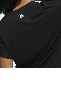 Černé tričko s krátkým rukávem, vyrobené z měkkého materiálu; na zadní straně se nachází bílé logo Adidas. Design je jednoduchý a moderní.
