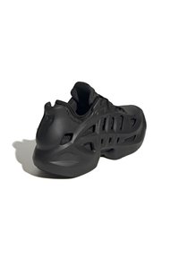 Scarpa sportiva nera con una struttura esterna scolpita e ventilata e un rivestimento interno imbottito in tessuto, vista da un angolo posteriore laterale.