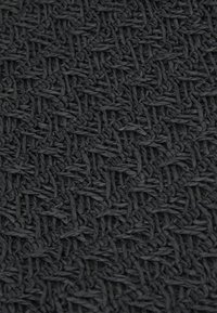 Detailní záběr na těsně tkané černé vlákna vytvářející texturovaný, mřížkový vzor s viditelnými propletenými prameny.