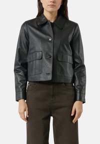 Schwarze, kürzere Lederjacke mit Knopfverschluss, spitzem Kragen und zwei aufgesetzten Fronttaschen. Glatte Textur mit tailliertem Schnitt.