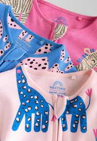 Tre beklædningsgenstande i blødt jersey-stof: pink med løveprint, blå med prikker og pink med blåt hånddesign. Runde halsudskæringer, printene er tydelige.