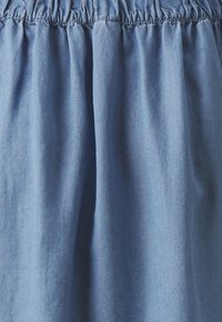 Jeansová sukně se shrnutým elastickým pasem. Světle modrá barva, hladká textura a jednoduchý design bez viditelných vzorů nebo kovových detailů.
