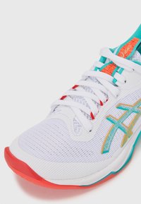 White athletic shoe with a mesh upper, turquoise and orange accents, textured sole, and turquoise and gold logo detailing.