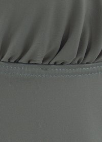 Sivi materijal s rebrastom teksturom, sa skupljenim detaljima na vrhu i kontrastnim šavovima duž rubova.