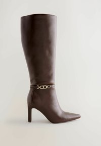 Knæhøj brun læderstøvle med spidse tæer og stiletto hæl. Har en guldtonet spænde rem omkring anklen for dekorativt element.