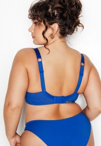 Soutien-gorge en dentelle bleue avec bretelles réglables et fermeture à agrafes. Tissu léger, texture lisse et dos sans coutures complètent les culottes hipsters assorties.