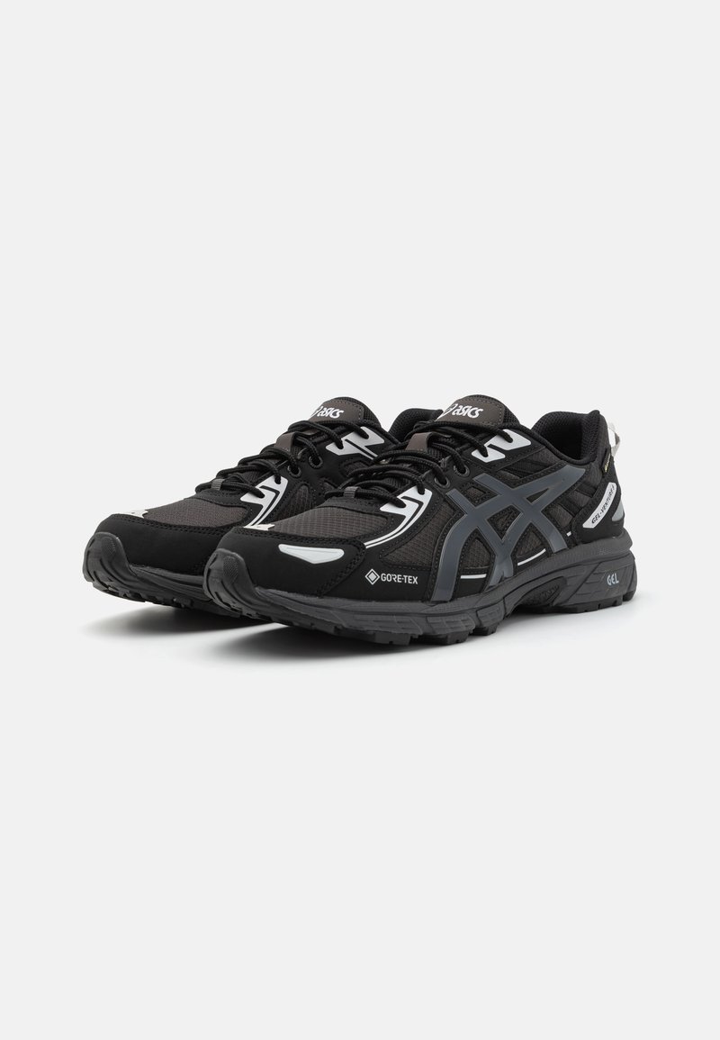 Schwarze Sportchuhe mit einem Obermaterial aus Mesh, reflektierenden Akzenten und einer strukturierten Gummisohle. Mit Gore-Tex-Branding für wasserdichte Leistung.