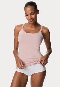Canottiera rosa chiaro con pizzo, spalline regolabili e vestibilità aderente, abbinata a slip bianchi. Tessuto morbido con una finitura liscia.