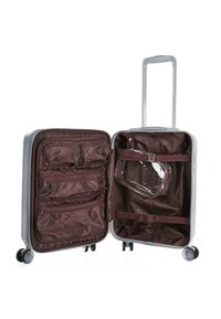 Maleta dura plateada con interior marrón, múltiples compartimentos con cremallera, correas ajustables y un neceser transparente.