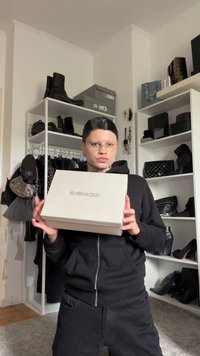 Biely darčekový box s nápisom "even&odd" vytlačeným čiernou farbou. Osoba v čiernej mikine drží box, na pozadí rôzne čierne doplnky.