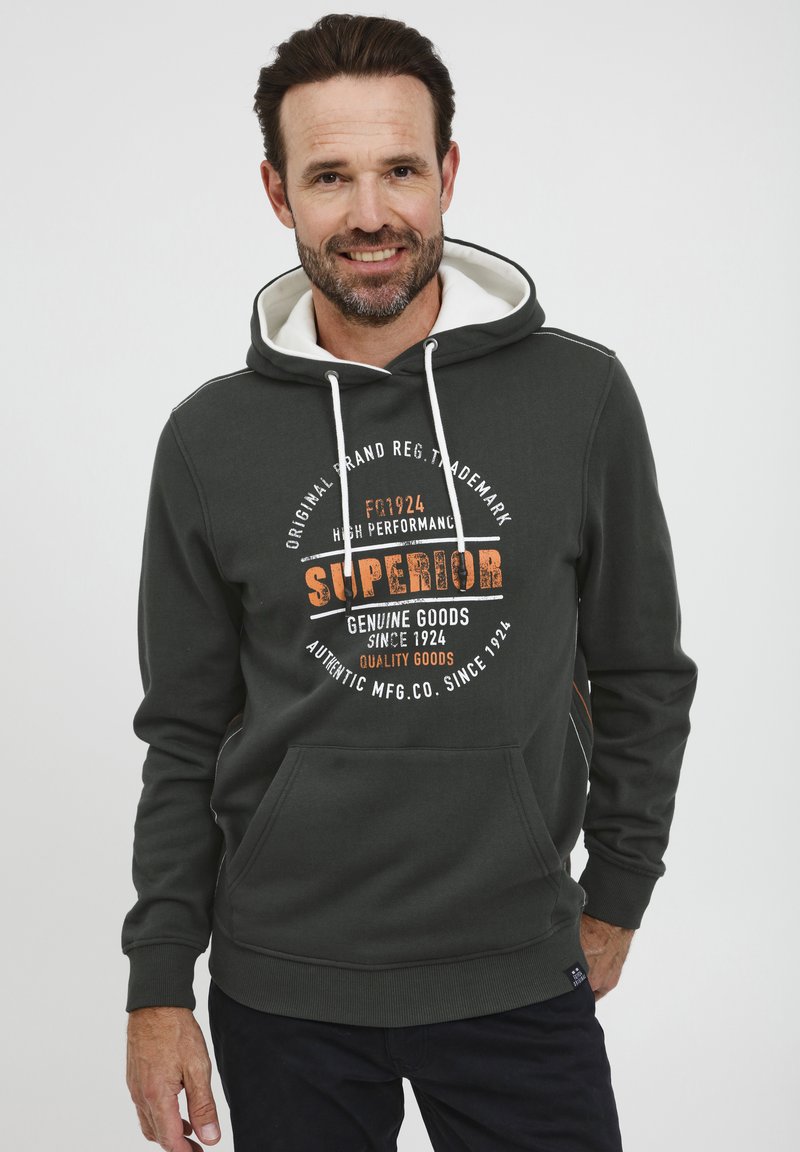 Sudadera verde oscura con forro blanco en la capucha, bolsillo frontal y texto impreso en naranja y blanco. Presenta puños y dobladillo acanalados.