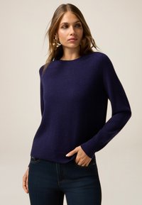 Granatowy sweter z wełny z okrągłym dekoltem, długimi rękawami i luźnym krojem. gładka tekstura z prążkowanymi mankietami i dołem.