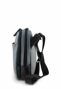 Sac en tissu gris avec accents noirs, comprenant deux compartiments zippés et une sangle d'épaule robuste. Forme compacte et rectangulaire.