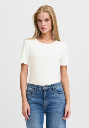 Weißes, geripptes, kurzärmeliges Oberteil mit rundem Halsauschnitt, kombiniert mit blauen, hoch taillierten Jeans im klassischen Fünf-Taschen-Design.