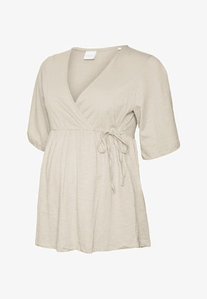 Beżowa krótka bluzka ciążowa z kopertowym przodem, wiązaniem w talii oraz luźnym, marszczonym materiałem poniżej biustu.