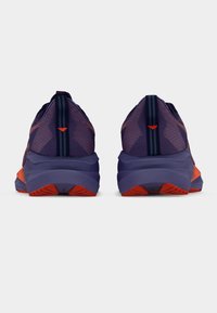 Zapatillas deportivas moradas con parte superior de malla texturizada, detalles en naranja y una suela acolchada con un patrón en zigzag en la suela exterior.