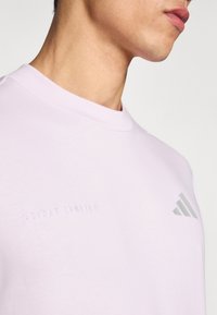 Heledad roosa lühikeste varrukatega Adidas Running t-särk ümar kaelusega, kaunistatud tikitud logoteksti ja peene tekstuuriga kangaga.