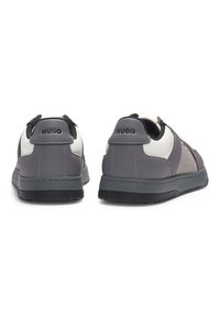 Pair of gray and white Hugo sneakers shown from the back, featuring black soles and Hugo logo on heel tabs.