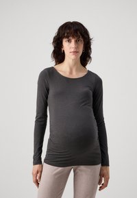 Gray long-sleeve maternity top featuring a rounded neckline and side ruching. Soft fabric with a smooth texture, paired with light-colored pants.